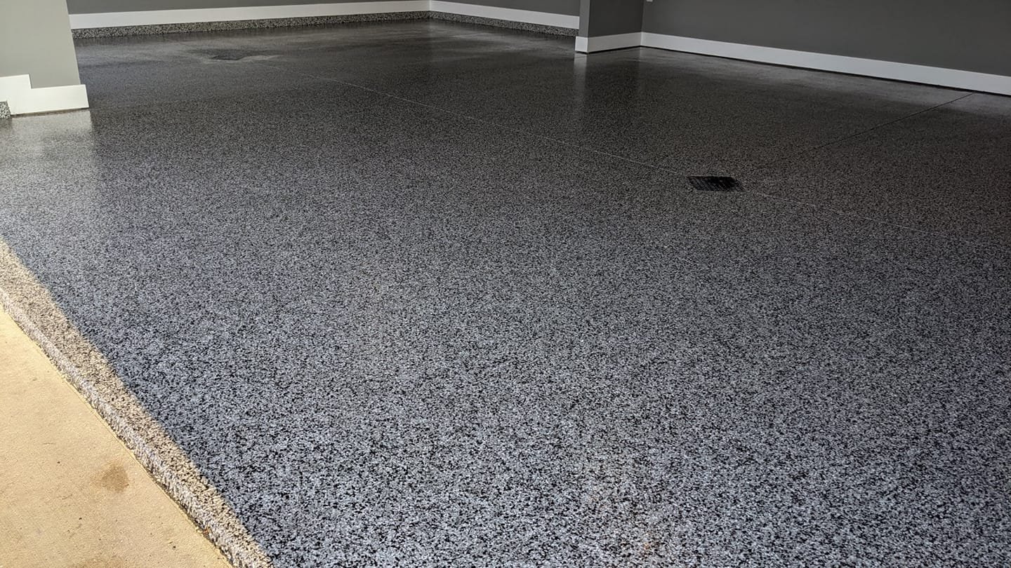 Epoxy coated garage floor with speckled gray and blue finish for a durable, polished surface.