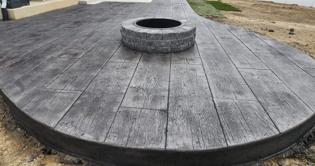 Wood-plank stamped concrete patio with a round fire pit near Fort Wayne, Indiana.