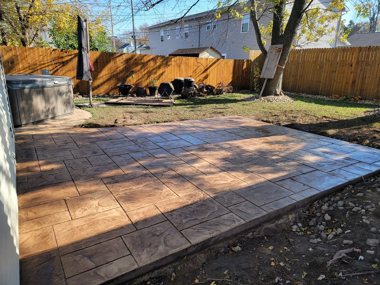 Freshly poured stamped concrete patio in a fenced backyard shaded by mature trees. Concrete patios in Wabash. Concrete patios in Hicksville.