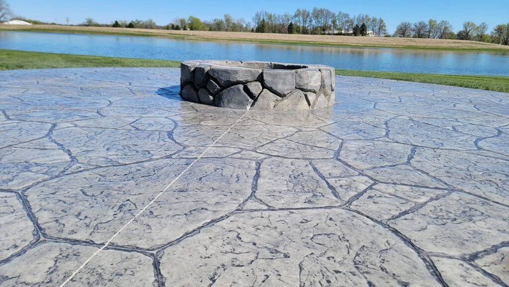Flagstone-pattern stamped concrete patio with a stone fire pit near Fort Wayne, Indiana.