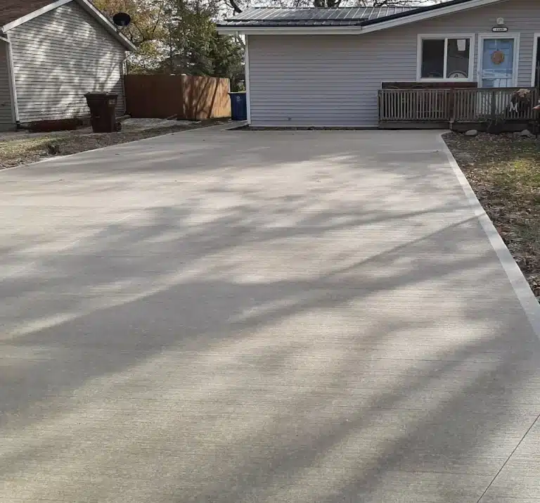 Smooth broom-finished concrete driveway in front of a residential garage, providing a clean, durable surface with subtle texture for traction.