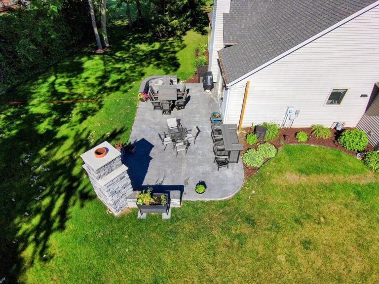 Aerial view of a backyard concrete patio with an outdoor fireplace in Pierceton, Indiana