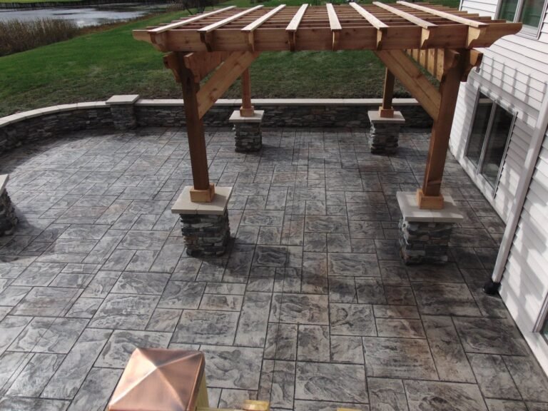 Concrete patio under a wood pergola with stone columns