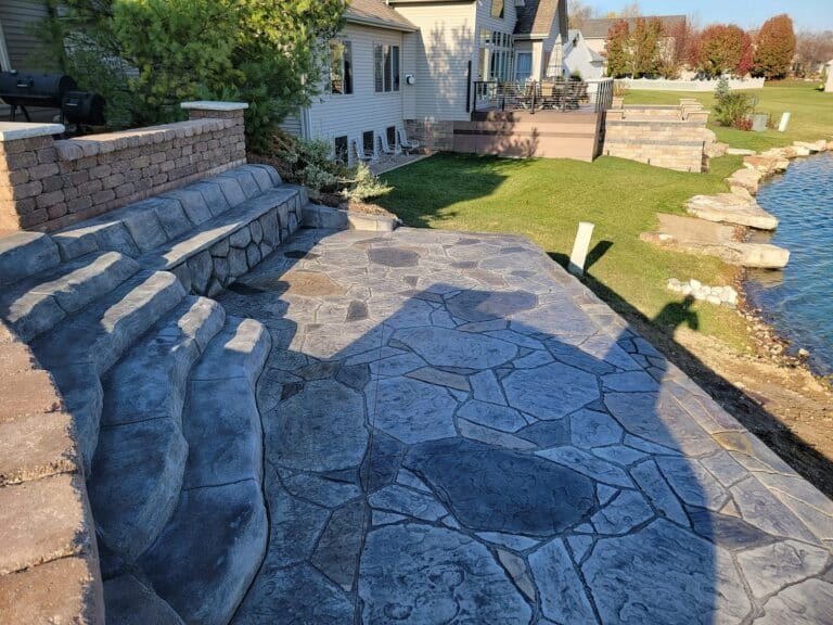 Flagstone-pattern stamped concrete patio with bench seating and curved steps