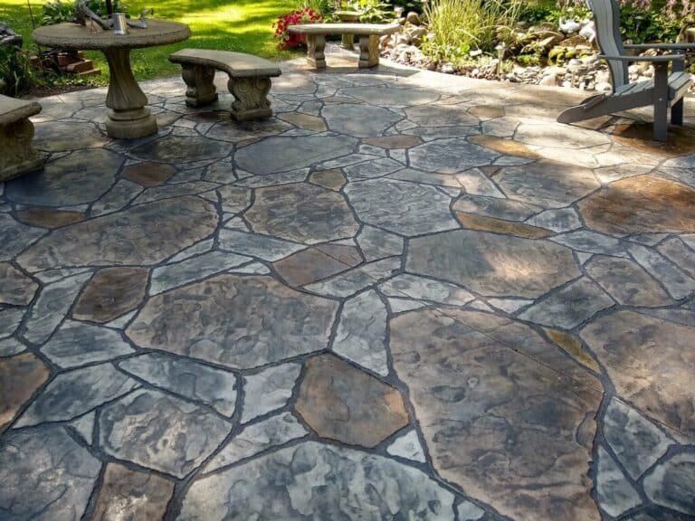 Natural stone pattern stamped concrete patio beside a garden bed