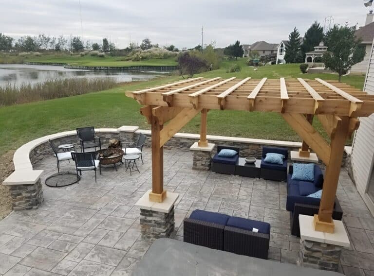 Stamped concrete patio with a pergola, seating wall and fire pit