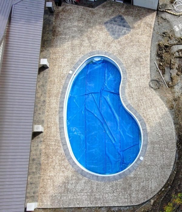 Kidney-shaped inground pool with concrete paver surround and stone edging, designed for backyard entertainment and leisure.