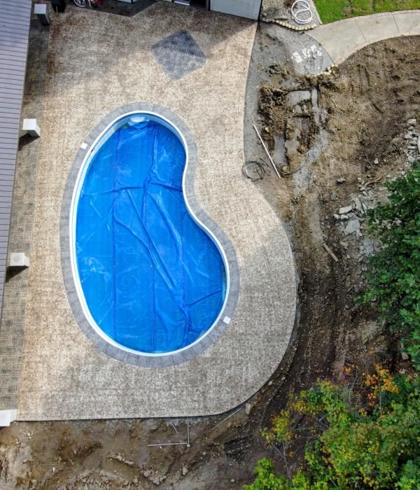Kidney-shaped inground pool with concrete paver surround and stone edging, designed for backyard entertainment and leisure.